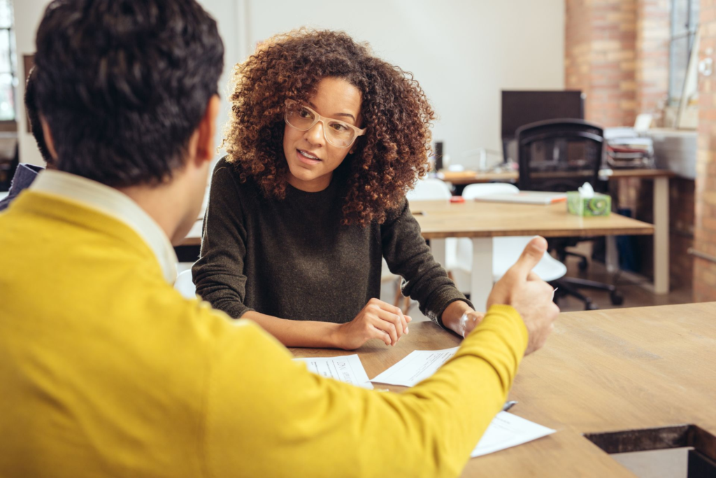 An office scene with a man and woman accountants deep in conversation at a table. An office scene with a man and woman accountants deep in conversation at a table.