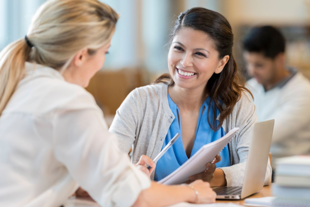 Two women accountants discussing financial matters in a library. Two women accountants discussing financial matters in a library.